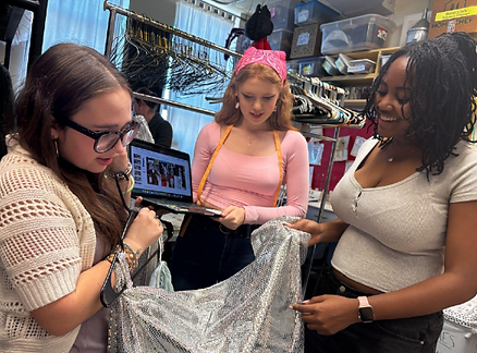 Costumes Co-Creheads, Rachel Mickey (left) and Lily Broglio (center), discuss costumes vision with senior Jayla Lee (right) who plays Hermes.